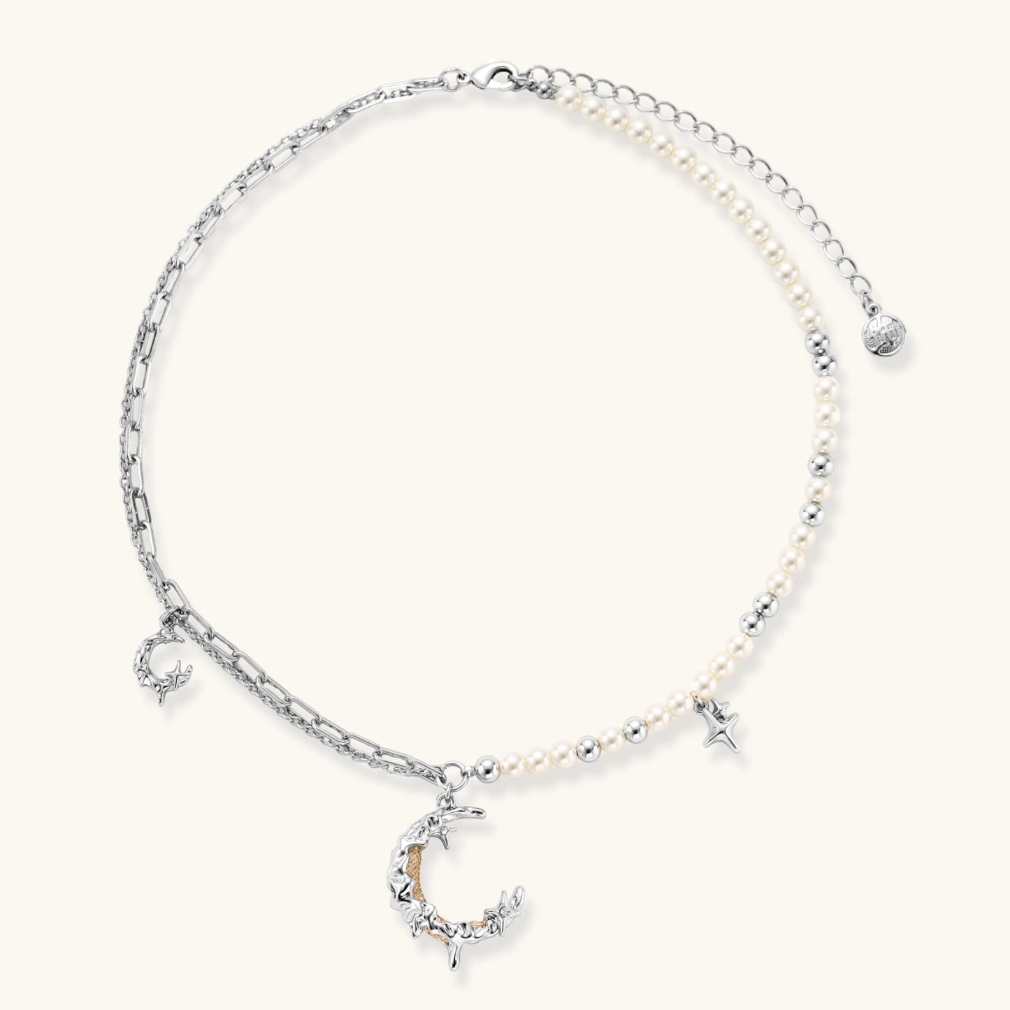 Silver-toned crescent moon pendant with star accents on pearl and chain necklace against white background.